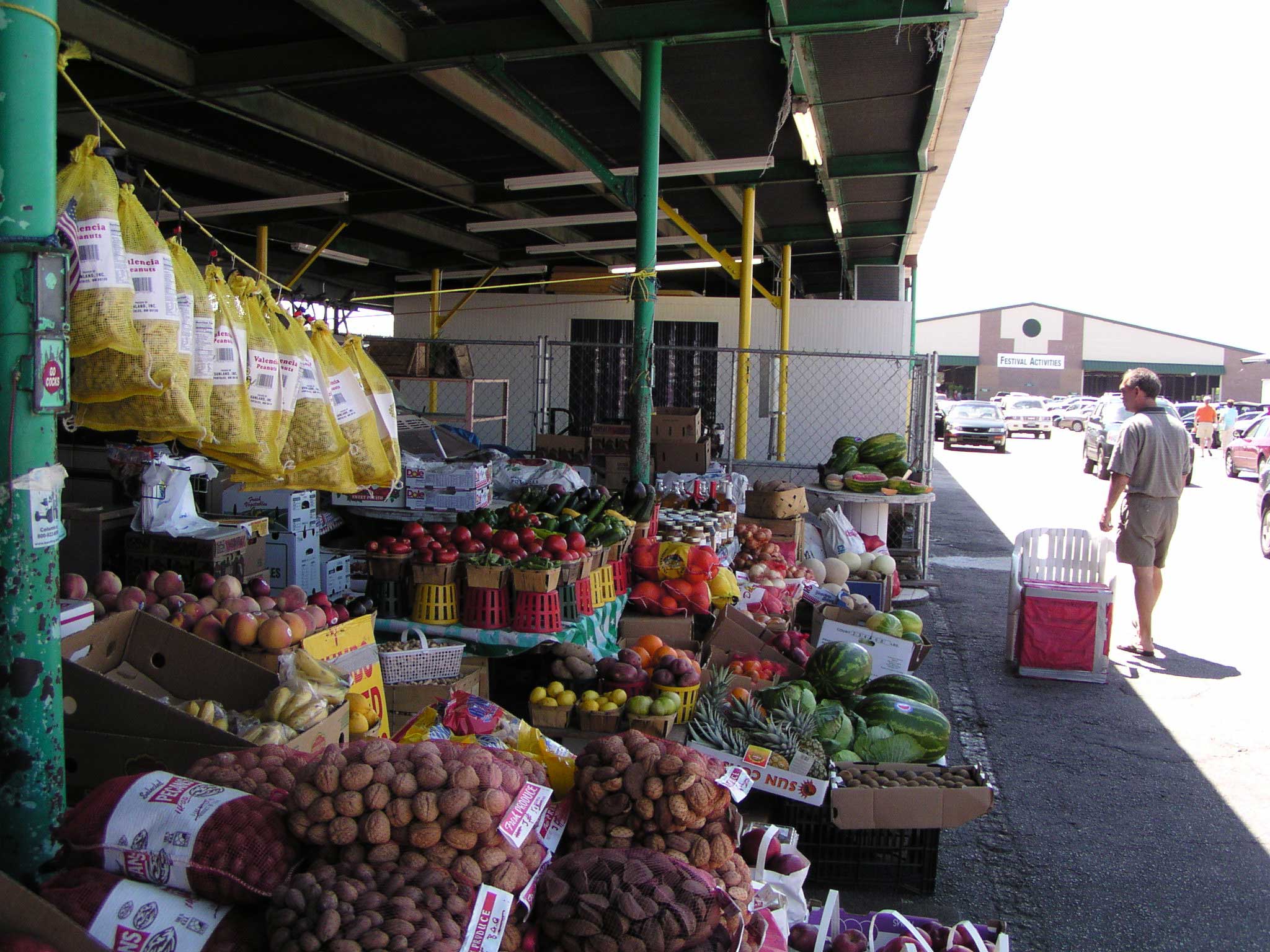 Produce displayed at a State Farmers Market stall in Columbia, South Carolina, with a shopper walking beside it.