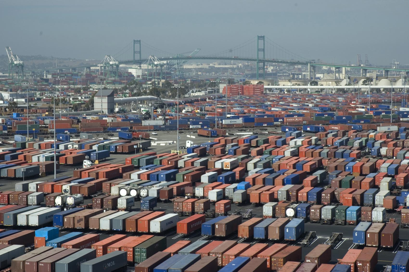 Elevated view across stacked shipping containers, cargo cranes, and the Vincent Thomas Bridge at the Port of Los Angeles and Long Beach in 2006.