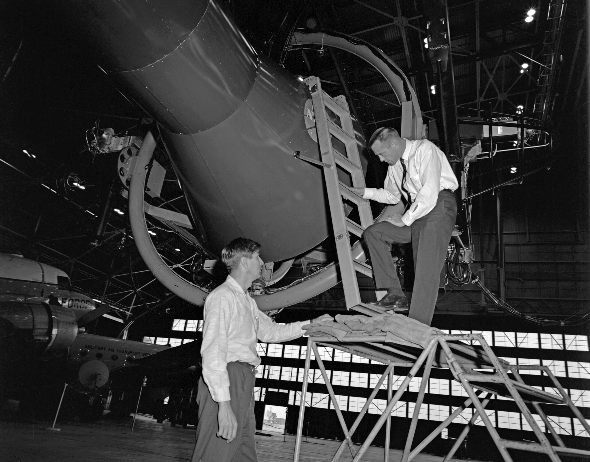 Alan Shepard entering a large NASA rendezvous and docking simulator in a hangar.