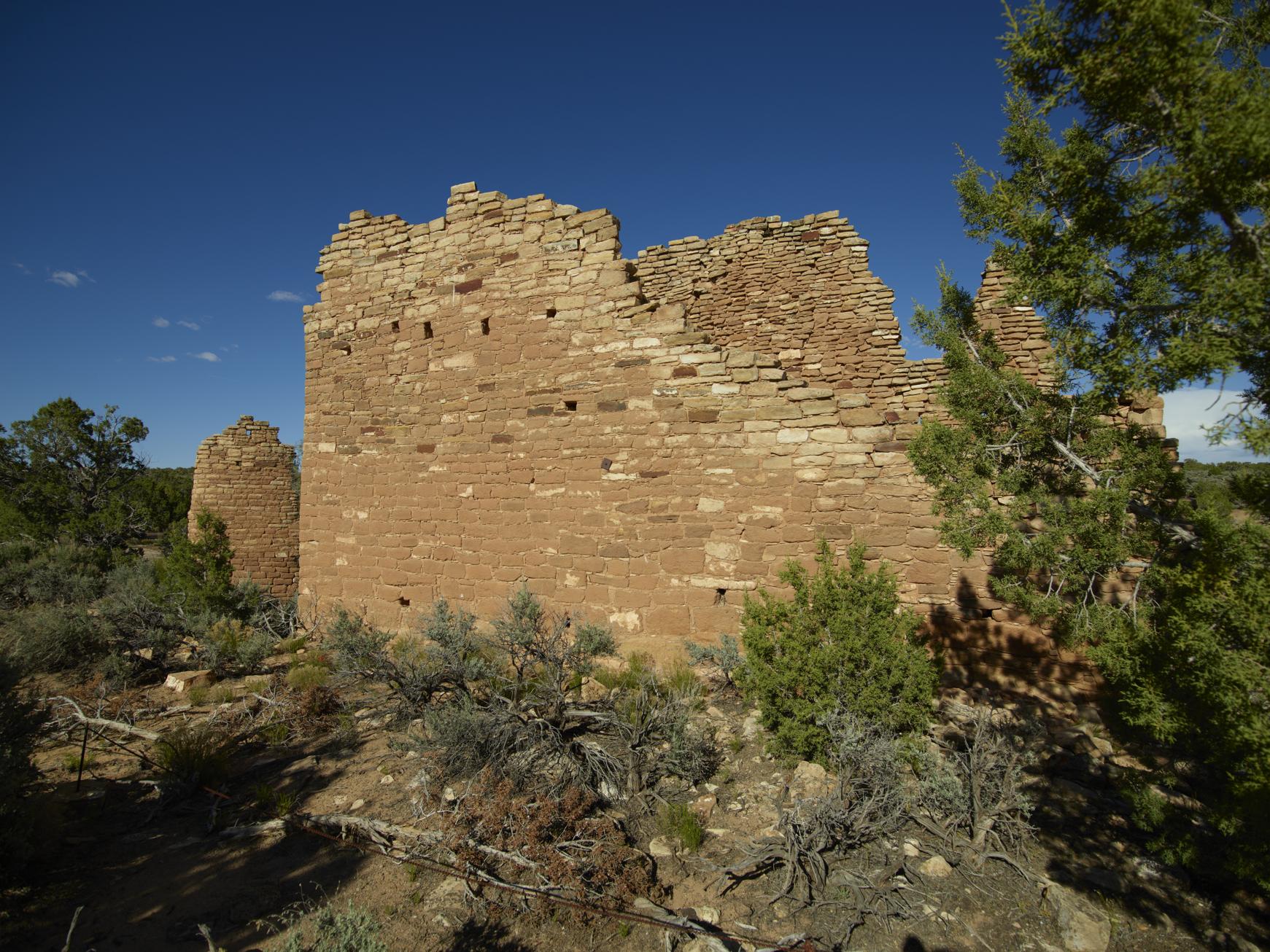 Masonry tower and standing walls at Hovenweep National Monument beneath a blue sky
